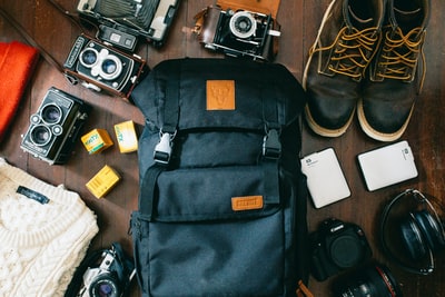 相机旁黑色包、便携式硬盘和黑色皮革系带靴的高角度照片